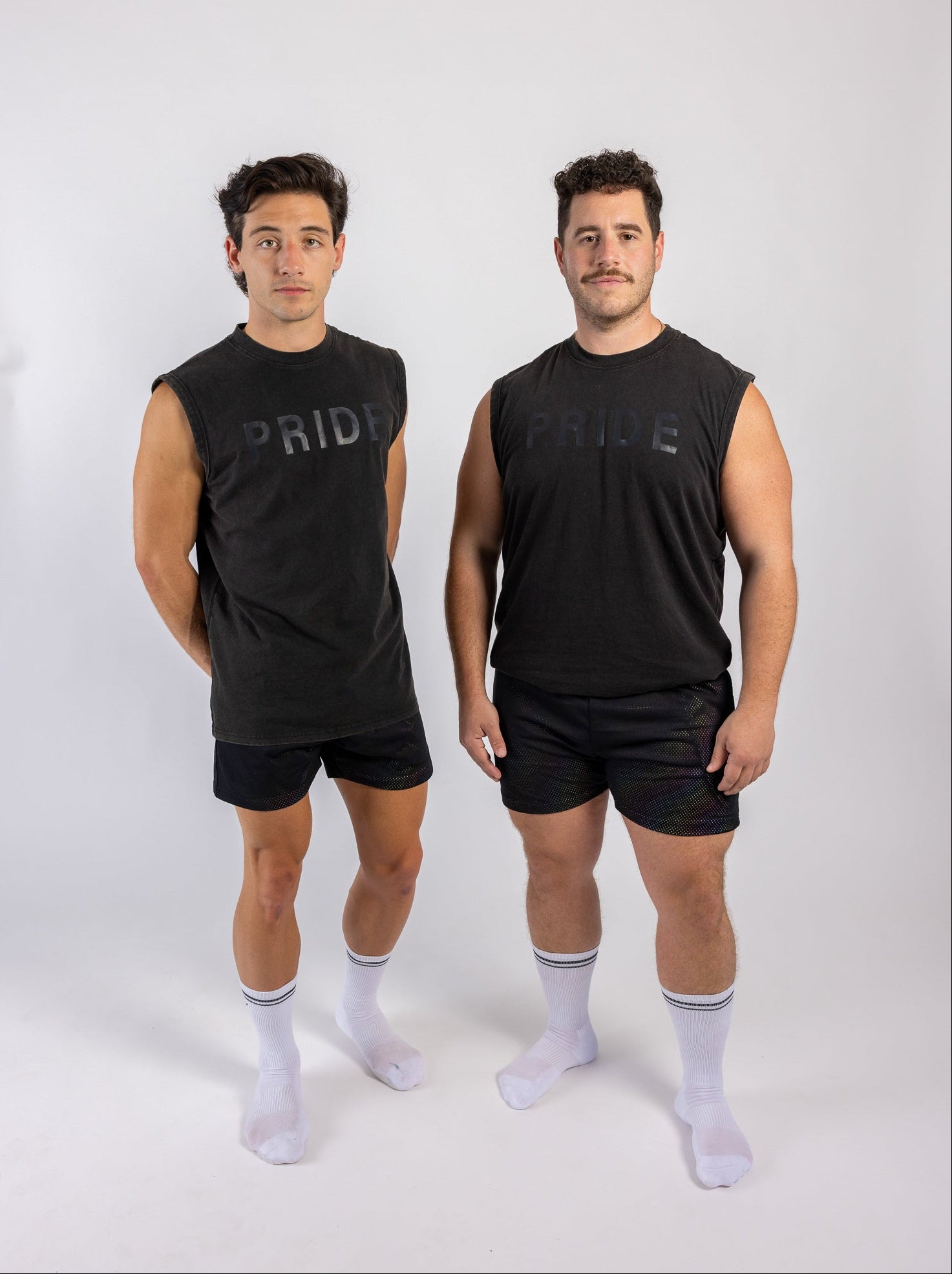 Two men wearing black sleeveless shirts with 'PRIDE' text on a white background
