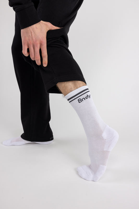 Person wearing black pants and white socks with a brand logo on a white background