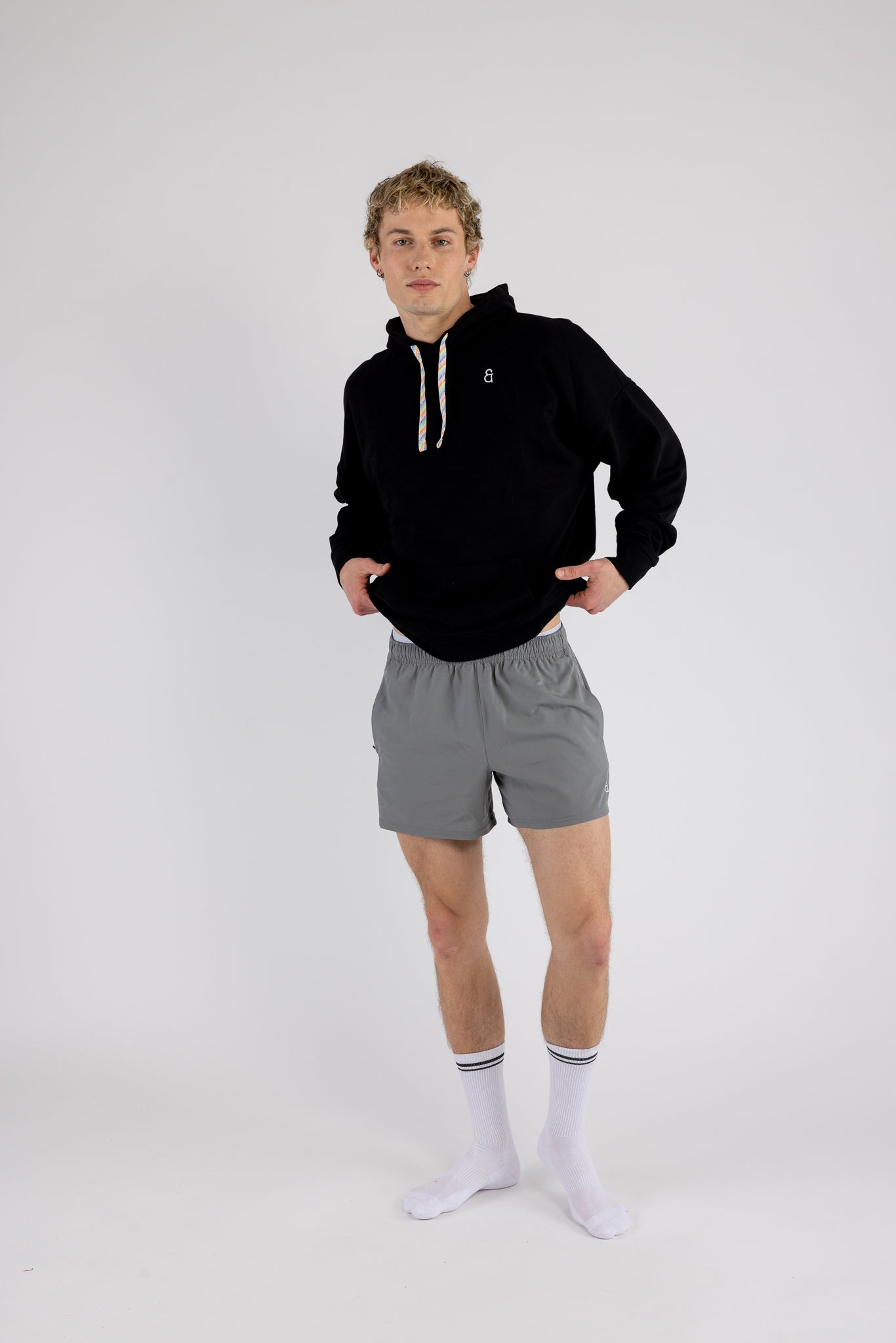 Man wearing Andy Prism Linerless Shorts 4" in Gray with black hoodie on white background
