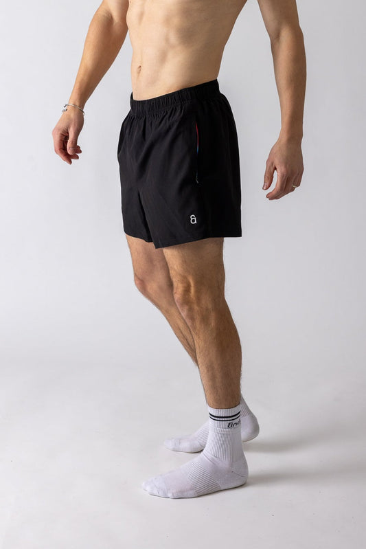 Man wearing black athletic shorts and a cap on a white background