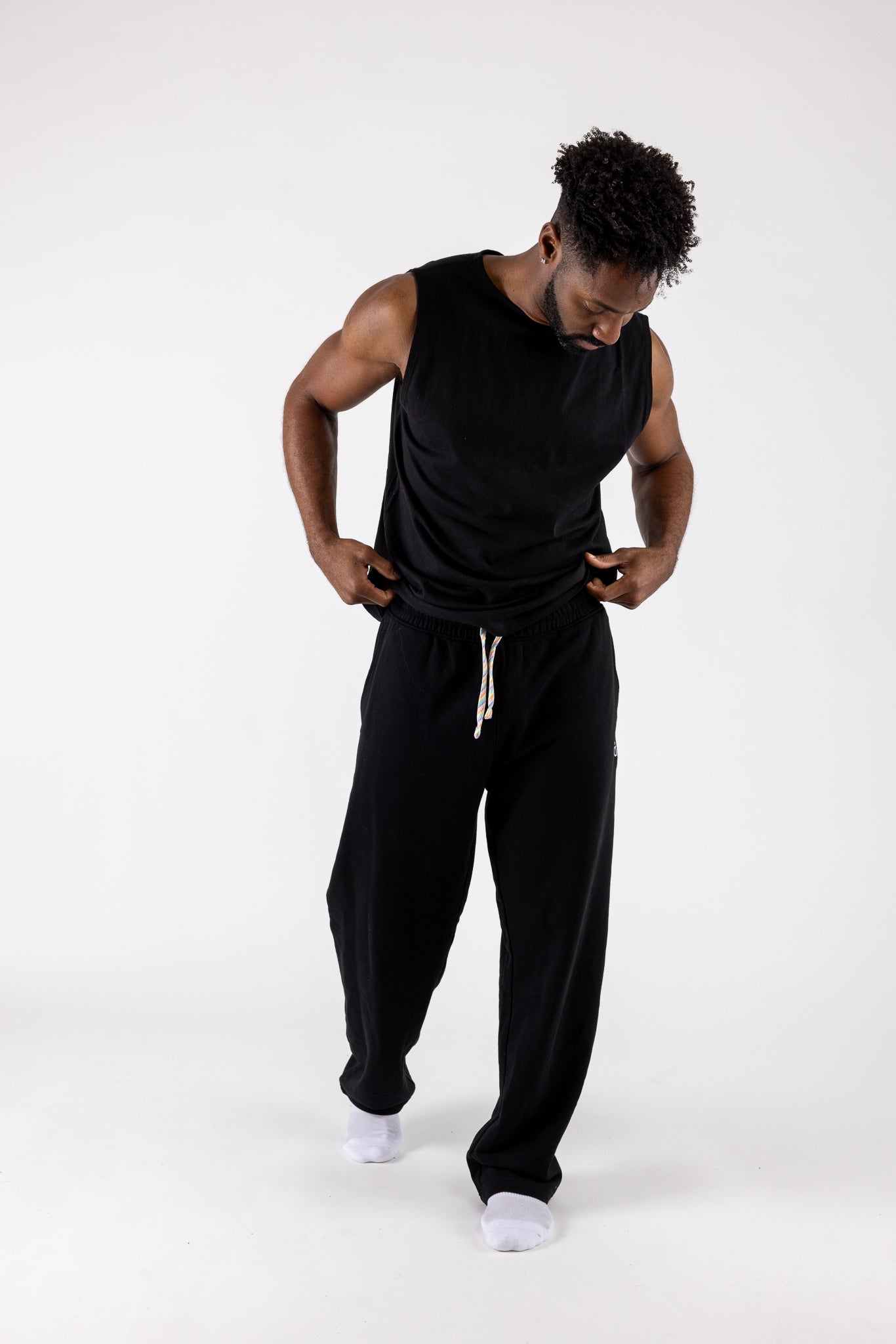 Man wearing a black sleeveless top and pants on a white background