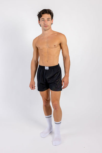Man wearing black boxer briefs and white socks on a white background