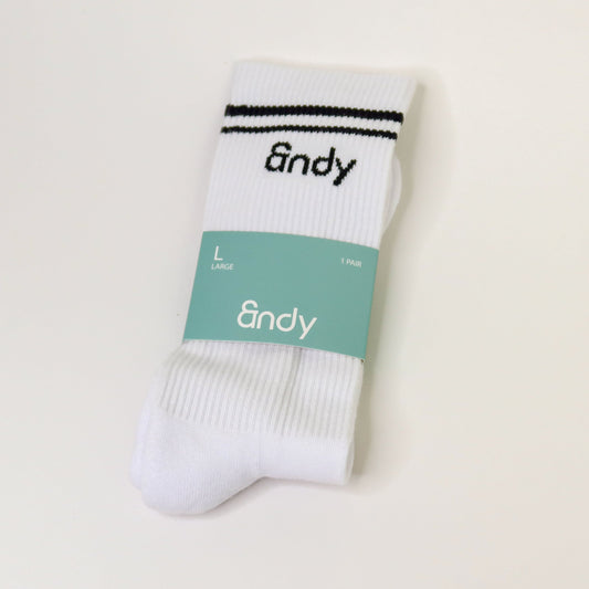 White sock with black stripes and 'andy' branding on a light beige background