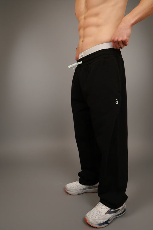 Person wearing black pants and white sneakers in a room with lockers.