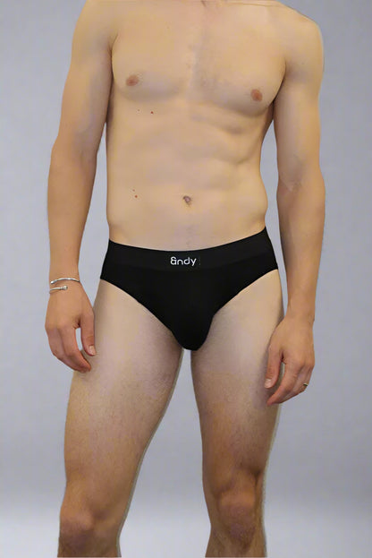Man wearing black briefs standing against a plain background
