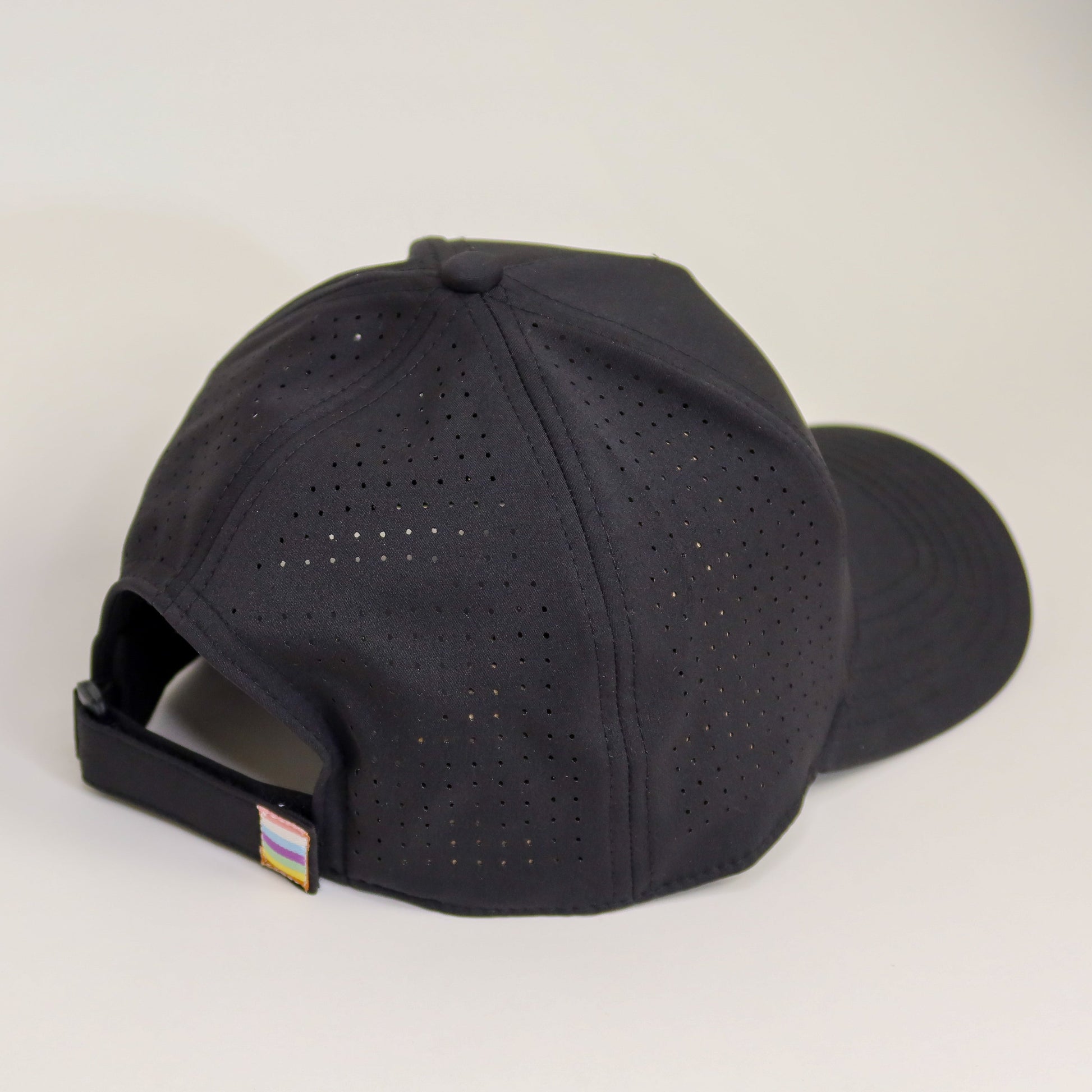 Black baseball cap with a small flag patch on a white background
